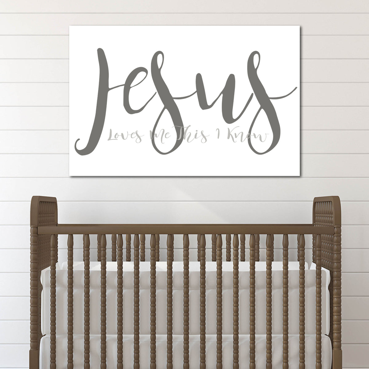 Wooden crib with a 'Jesus Loves Me This I Know' sign on a white wall.