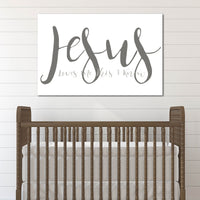 Wooden crib with a 'Jesus Loves Me This I Know' sign on a white wall.