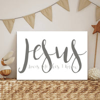 Decorative sign with 'Jesus Loves Me This Much' text in a home setting with bunting and decor items.