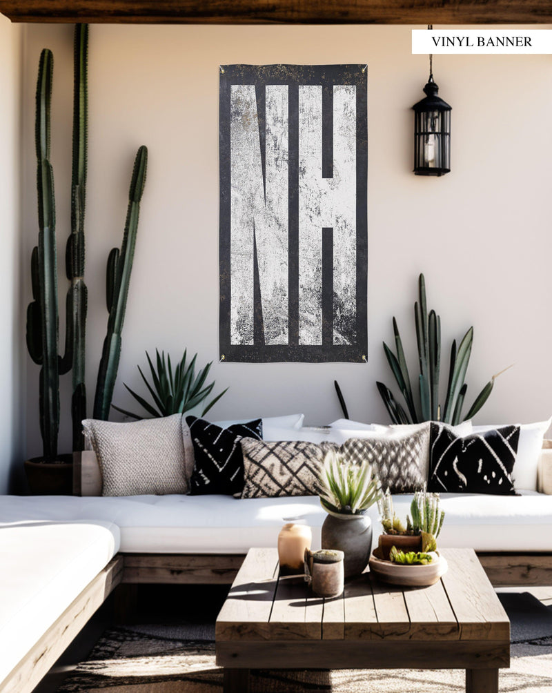 "Chic 'NH' banner, blending minimalist design with practicality, celebrates New Hampshire's charm in any setting, from outdoor areas to cozy indoor corners."